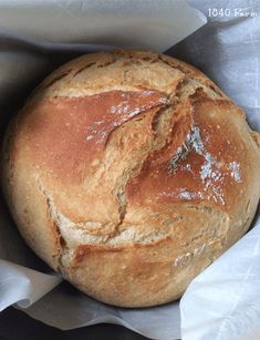 a loaf of bread sitting on top of a piece of wax paper in a basket