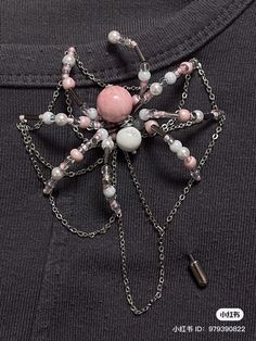 a pink and white brooch with chains attached to it