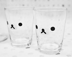 two glasses with faces drawn on them are sitting on a polka dot tablecloth surface