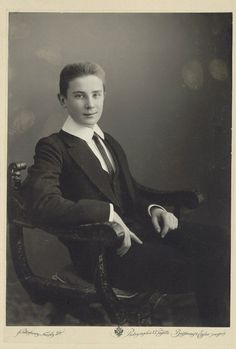 an old black and white photo of a man in a suit sitting on a chair