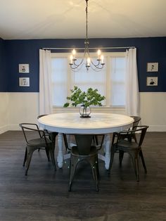 a dining room table with four chairs and a potted plant on top of it