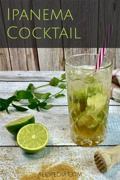 a glass filled with lemonade and lime next to a wooden spoon on top of a table