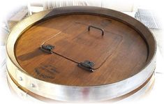 a wooden barrel sitting on top of a table next to a metal container with two handles