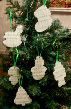 a small christmas tree decorated with white paper cutouts and green ribbon hanging from it's branches