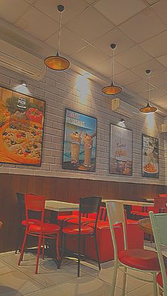 an empty restaurant with red chairs and posters on the wall above it's tables