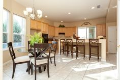 a kitchen and dining room with tile flooring in an open concept home, which is well lit by sunlight coming through the windows