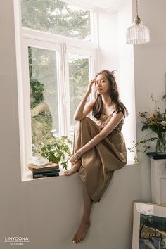 a woman sitting on a window sill looking out the window