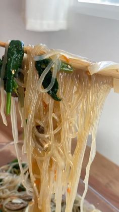 the noodles are being held up by chopsticks