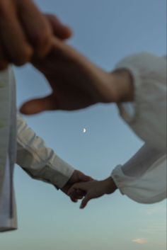 two people holding hands with the sky in the background