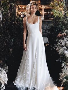 a woman in a white dress standing next to flowers