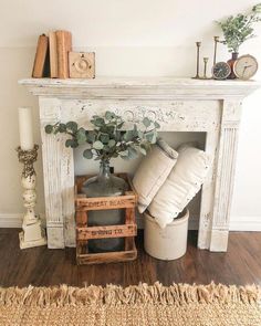 a white fireplace mantel with pillows and candles