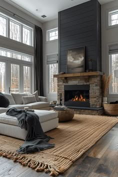 a living room with a fire place and couches in front of large windows that look out onto the woods