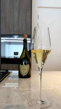 a glass of wine sitting on top of a counter next to a bottle of wine