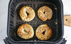 four bagels sitting on top of an air fryer with poppy seed sprinkles