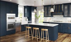 a large kitchen with blue cabinets and white counter tops, wooden flooring and stools