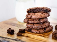 a stack of cookies sitting on top of a wooden table next to a glass of milk