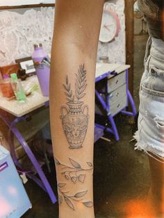 a woman's leg with a tattoo on it and an image of a vase