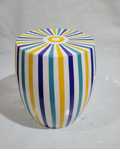 a colorful striped stool sitting on top of a white table