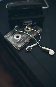 an ipod and headphones are sitting on a black table next to a cassette player