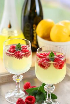 two glasses filled with lemonade and raspberries