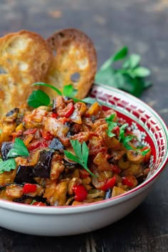 a bowl full of food with bread on the side