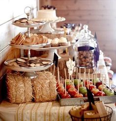 an assortment of desserts and pastries are displayed on a buffet table with straw bales