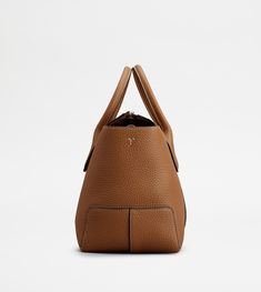 A central ribbing and tubular handles characterize this elegant shopping bag with Tod's logo stamped on the front. Featuring an internal pouch and removable shoulder strap, it is crafted in soft calfskin leather. To accompany with class and femininity your everyday outfits. Tods Bag, Area Codes, Logo Stamp, Bago, Everyday Outfits, Bucket Bag, Calf Skin, Dust Bag, Shoulder Strap