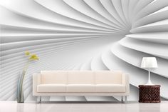 a white couch sitting in front of a wall with an abstract design on it's side