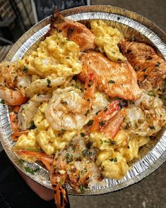 a person holding a plate of food with shrimp and macaroni