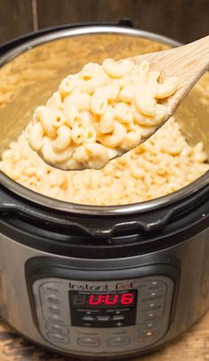 a wooden spoon full of macaroni and cheese in an instant pot with the lid open