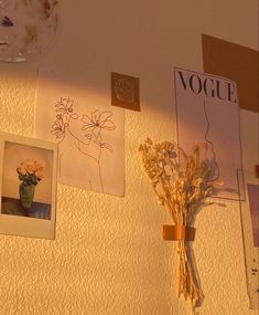 flowers and pictures are hanging on the wall in front of a light that is dim