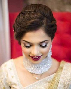 a woman in a white and gold sari with pearls on her head