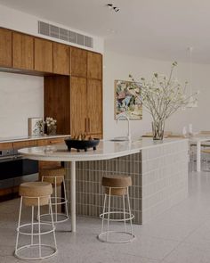 a kitchen with two stools next to a counter top and an island in the middle