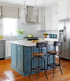 a kitchen with two stools at the island