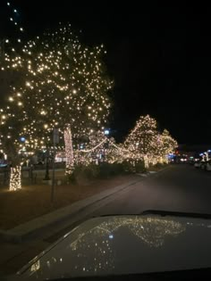 a car is parked on the side of the road covered in christmas lights and trees