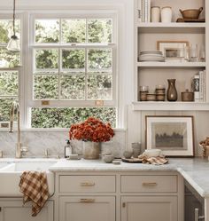 a kitchen filled with lots of white cabinets and counter top space next to a window