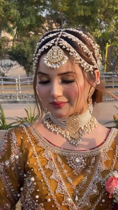 a woman wearing a bridal outfit with jewelry on her neck and headpieces