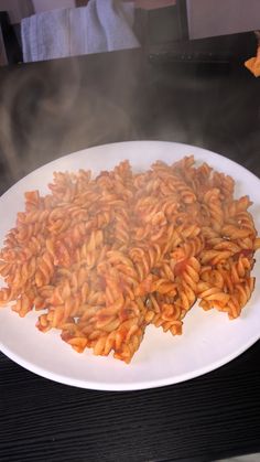 a white plate topped with lots of pasta on top of a table next to a frying pan