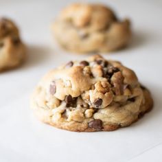 three chocolate chip cookies sitting on top of white paper