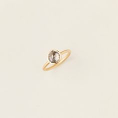 a yellow gold ring with a grey diamond on it's side, against a white background