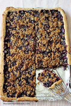 a blueberry crumbled pie on a table with a fork next to it