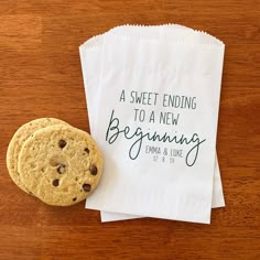 a cookie sitting on top of a napkin next to a paper bag that says, a sweet ending to a new beginning