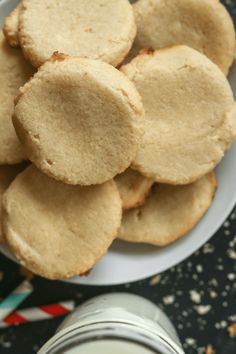 some cookies are on a white plate next to a glass of milk and a can