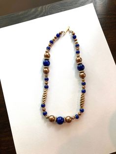 "Vintage Signed V.A. Navy and Bronze Beaded Necklace. The beads of this necklace are plastic. There are some gold tone spacers and bead caps. There are bronze small beads and larger beads and twisted beads. The navy blue beads are also a variety of sizes. The clasp is a simple hook signed V.A.  It is 18\" long. It looks like a heavier necklace then what it is. It is in excellent condition. No missing beads, no chips, no scratches or color discolor." Gold Necklaces With Polished Metal Beads, Gold Necklaces With Metal Beads, Elegant Gold Metal Beaded Necklaces, Elegant Gold Beaded Necklaces With Metal Beads, Gold Metal Beads With Large Beads, Gold Beaded Chain Metal Necklaces, Gold Metal Beaded Chain Necklace, Gold Metal Beads Necklace For Jewelry Making, Gold Large Beads Costume Jewelry Necklace