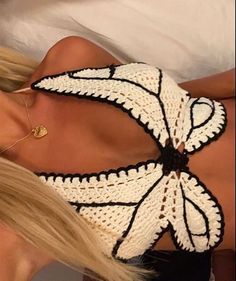 a woman laying in bed wearing a black and white crochet top with an open back