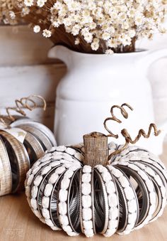 a white pumpkin sitting on top of a wooden table next to some vase filled with flowers