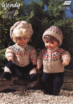 two dolls sitting next to each other in knitted clothes and hats with flowers on them