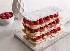 a stack of strawberry shortcakes with powdered sugar and raspberries on top