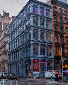 people are walking on the street in front of an old building with a fire escape