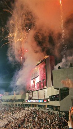 fireworks are lit up in the air above a crowd at a sporting event as people watch